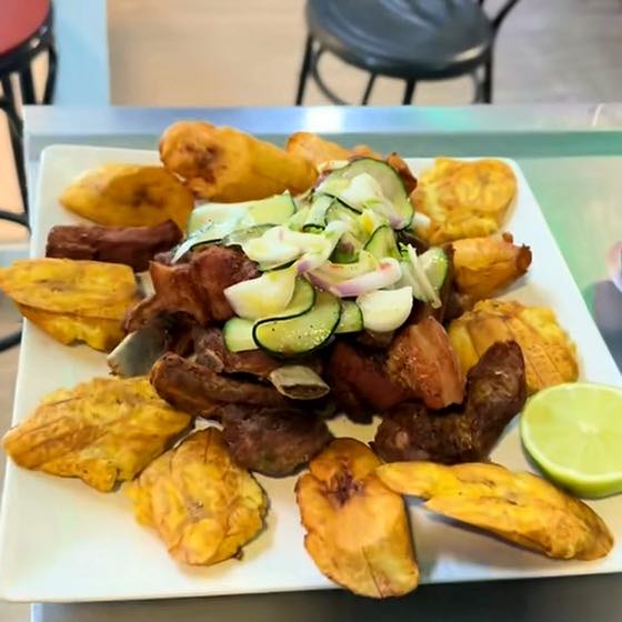Carne frita con patacones, curtido de pepino y cebolla morada.